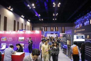 Público asistente en un auditorio oscuro presenciando el escenario iluminado con luces azules del evento Blockchain Life en Dubái.