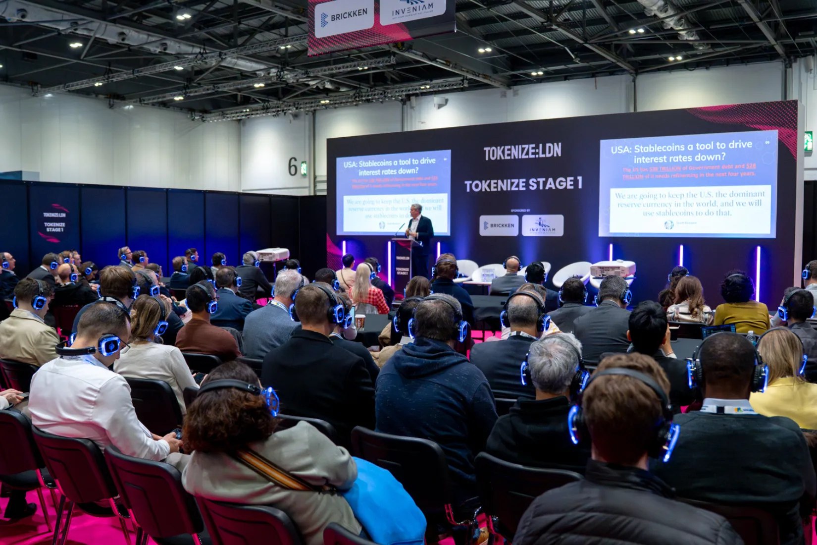 Público asistente con auriculares inalámbricos escuchando una ponencia sobre stablecoins en el escenario principal del evento TOKENIZE:LDN.