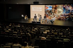 Panel de discusión en el escenario principal del evento Watch Out, Bitcoin! frente a la audiencia.