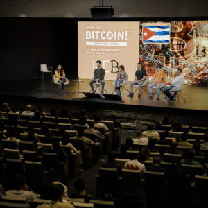 Panel de discusión en el escenario principal del evento Watch Out, Bitcoin! frente a la audiencia.