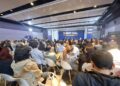 Grupo de personas en un salón escuchando la intervención del cofundador de Coinbase
