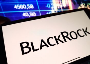 Un celular que muestra el logo de BlackRock delante de una pantalla de precios.