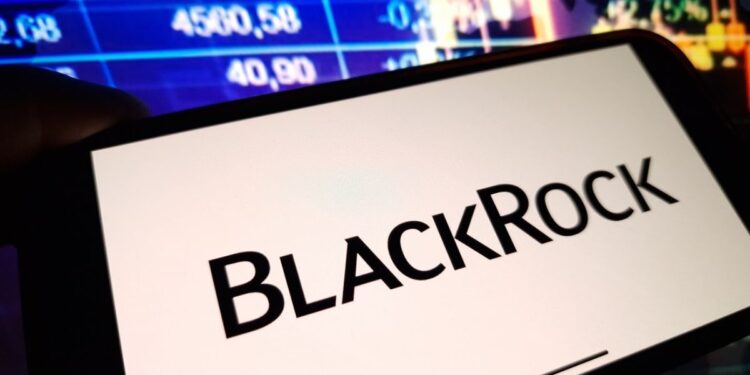 Un celular que muestra el logo de BlackRock delante de una pantalla de precios.