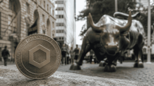 En primer plano: moneda fรญsica con el logo de Chainlink. En el fondo: imรกgenes tรญpicas de Wall Street.