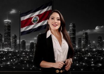 La abogada Stephanie Sánchez posa para la foto y al fondo hay una bandera de Costa Rica y edificios estilo rascacielos.