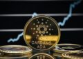 Moneda fรญsica de ADA en un escritorio, con fondo negro y una lรญnea de grรกfico en blanco.