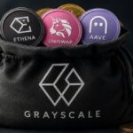 Criptomonedas físicas de ethena, uniswap y aave dentro de una bolsa que tiene el logo de Grayscale.