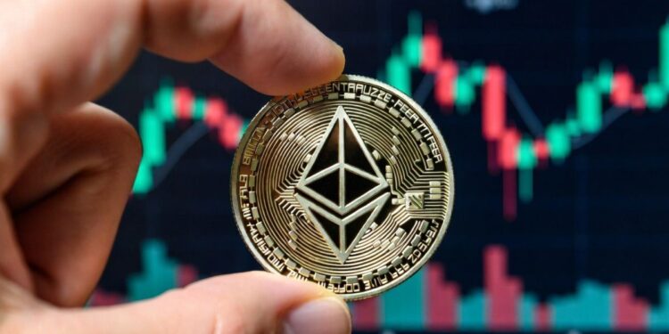 Mano sosteniendo una moneda física de Ethereum con gráficos bursátiles en el fondo.