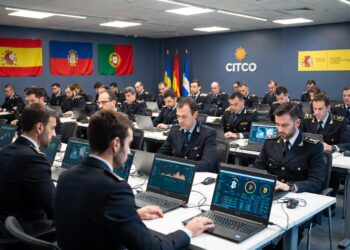 Agentes policiales aparecen sentados cada uno frente a una computadora en la que se observa información sobre bitcoin y criptomonedas