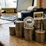 Monedas apiladas con el logo de Western Union sobre un escritorio.