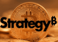 En primer plano: logo de Strategy. En el fondo: moneda de bitcoin.