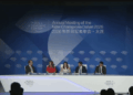 Fotografía de un escenario iluminado durante una conferencia internacional del Foro Económico Mundial. Cuatro panelistas, vestidos con trajes ejecutivos formales, están sentados en sillones individuales manteniendo una discusión.