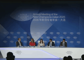 Fotografía de un escenario iluminado durante una conferencia internacional del Foro Económico Mundial. Cuatro panelistas, vestidos con trajes ejecutivos formales, están sentados en sillones individuales manteniendo una discusión.