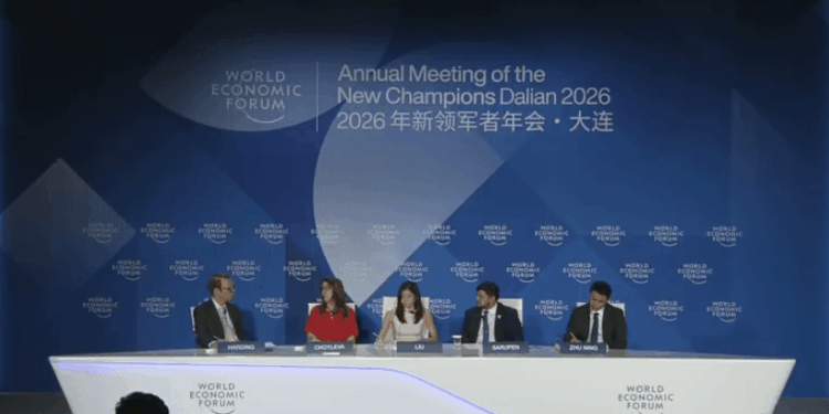 Fotografía de un escenario iluminado durante una conferencia internacional del Foro Económico Mundial. Cuatro panelistas, vestidos con trajes ejecutivos formales, están sentados en sillones individuales manteniendo una discusión.