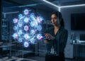 Una mujer enfocada trabajando en un laboratorio tecnológico oscuro. Con sus manos interactúa con una interfaz holográfica brillante de tonos azules y morados que representa un complejo modelo de computación cuántica con esferas interconectadas. En la esquina inferior de la pantalla de cristal transparente se lee: 'D-Wave Quantum Simulator: Leap Platform September 2026 Availability'