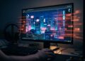 Vista en primera persona de un usuario frente a un monitor de computadora en una habitación a oscuras. La pantalla muestra un atractivo fondo de pantalla animado de una ciudad cyberpunk, pero está superpuesta con flujos de código binario rojo brillante que parecen escapar de la pantalla hacia el mundo real. La imagen simboliza un software malicioso oculto operando en segundo plano y robando datos mientras el usuario interactúa confiadamente con un programa de apariencia inofensiva.