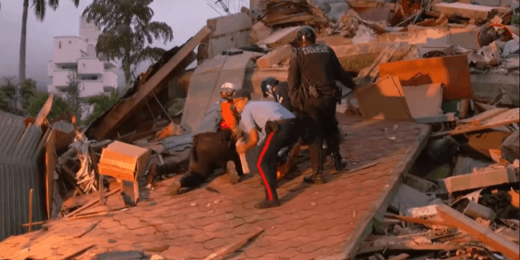 Fotografía del Terremoto en Venezuela. En la imagen se observa a cuatro rescatistas y funcionarios de seguridad pública, uno de ellos con la inscripción "POLICÍA CHACAO" en la espalda de su chaqueta negra, avanzando con precaución sobre una gran sección de techo derrumbada.