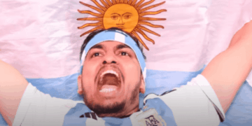 Aficionado argentino con bandera y bandana celeste y blanca en la cabeza, celebrando antes de un partido del Mundial 2026.