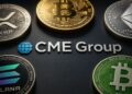Monedas físicas de bitcoin, ether, xrp, solana y bitcoin cash alrededor del logo de CME Group.
