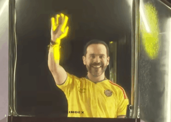 Fotografía en plano medio de Abelardo de la Espriella hablando frente a un micrófono durante su discurso de victoria en Barranquilla. Viste camiseta de la sección de Colombia, gesticula con una mano en actitud firme y pantallas con iluminación del evento.