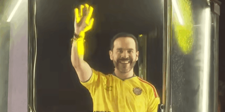 Fotografía en plano medio de Abelardo de la Espriella hablando frente a un micrófono durante su discurso de victoria en Barranquilla. Viste camiseta de la sección de Colombia, gesticula con una mano en actitud firme y pantallas con iluminación del evento.