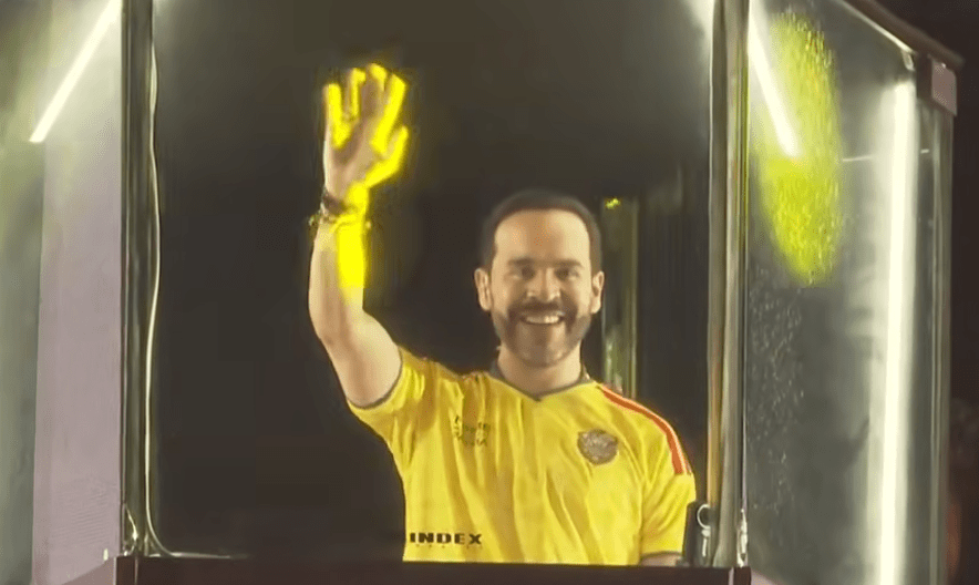 Fotografía en plano medio de Abelardo de la Espriella hablando frente a un micrófono durante su discurso de victoria en Barranquilla. Viste camiseta de la sección de Colombia, gesticula con una mano en actitud firme y pantallas con iluminación del evento.