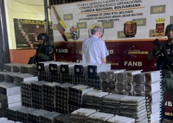 Fotografía de funcionarios de la GNB junto a un detenido y cientos de mineros ASIC.
