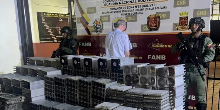 Fotografía de funcionarios de la GNB junto a un detenido y cientos de mineros ASIC.