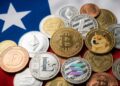 Monedas físicas de bitcoin y criptomonedas sobre la bandera de Chile.