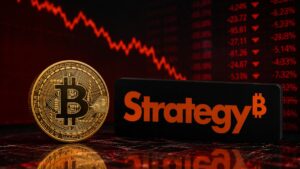 Moneda de bitcoin frente al logo de Strategy con gráficos bajistas en rojo.