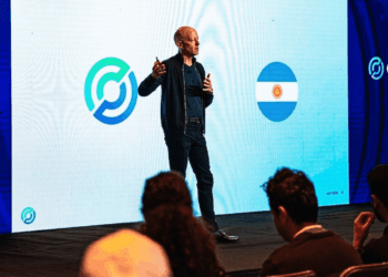 Una fotografía de Jeremy Allaire, CEO de Circle, de pie en un escenario y dando una presentación. Allaire, vestido con una chaqueta oscura y pantalones oscuros, sostiene un micrófono y gesticula con las manos mientras habla.