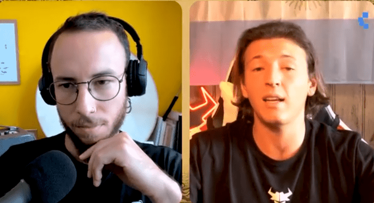 Una captura de pantalla dividida de una entrevista de video. En el lado izquierdo, Iván Gómez, un hombre con gafas, barba corta y auriculares negros sobre las orejas, mira hacia abajo pensativamente con su mano derecha sobre su barbilla. Viste una camiseta negra y está sentado frente a una pared de color amarillo brillante. A la derecha, Micael Margiotta, un hombre de cabello oscuro y lacio hasta los hombros, habla directamente a la cámara con una expresión seria y la boca ligeramente abierta.