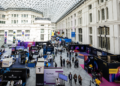 Feria tecnológica Merge Madrid 2025, con stands de criptomonedas y fintech en un gran recinto acristalado.