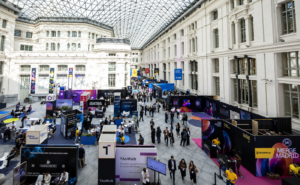 Feria tecnológica Merge Madrid 2025, con stands de criptomonedas y fintech en un gran recinto acristalado.