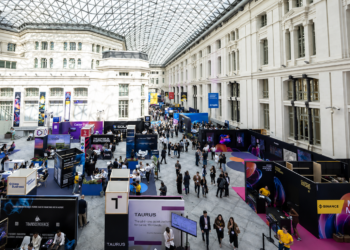 Feria tecnológica Merge Madrid 2025, con stands de criptomonedas y fintech en un gran recinto acristalado.