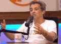 Fotografía de plano medio del activista e informático alemán Michael Ballweg mientras conversa en el podcast "En vivo desde Bitcoin Beach El Salvador". Viste una camiseta blanca abierta sobre una camiseta blanca que lleva impresa la palabra Rebell, (rebelde) escrita con B de Bitcoin.
