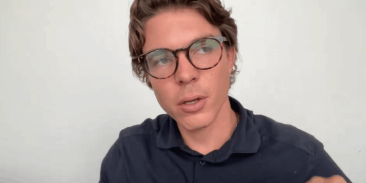 Primer plano de Oriol Blanch de Bitvavo, un hombre joven con gafas de carey y camisa polo azul oscuro, hablando y mirando hacia la izquierda del encuadre contra un fondo de pared blanca plana.