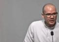 Rodrigo Icaza, hombre calvo con lentes de marco negro, viste camisa blanca y habla ante un micrófono durante una conferencia.
