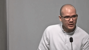 Rodrigo Icaza, hombre calvo con lentes de marco negro, viste camisa blanca y habla ante un micrófono durante una conferencia.