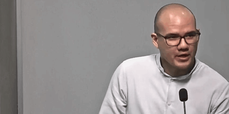 Rodrigo Icaza, hombre calvo con lentes de marco negro, viste camisa blanca y habla ante un micrófono durante una conferencia.