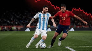 Lionel Messi con la camiseta de Argentina y Rodrigo Hernández con la de España disputan el balón en un partido de fútbol, mientras en el fondo negro destaca un enorme gráfico rojo de caída financiera.