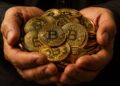 Primer plano de dos manos sosteniendo un puñado de monedas de bitcoin doradas.