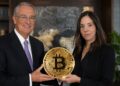 Ricardo Salinas y Lyn Alden sosteniendo una moneda de bitcoin dorada.