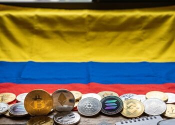 Fotografía de la bandera de Colombia con criptomonedas alrededor.