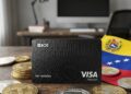 Tarjeta de OKX en una mesa con la bandera de Venezuela y monedas de USDT.