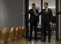 Personas de traje impidiendo el paso a monedas de bitcoin a una sala.