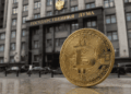 Moneda física de bitcoin delante de la Duma de Rusia.