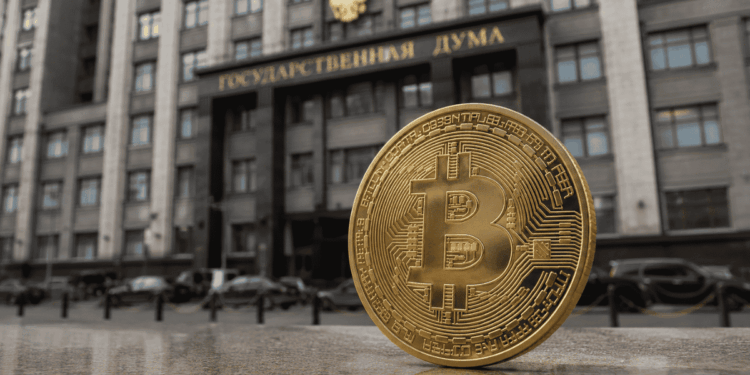 Moneda física de bitcoin delante de la Duma de Rusia.