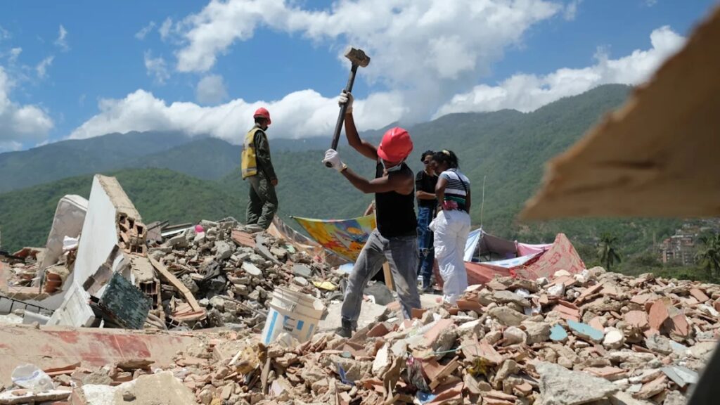 Fotografía de rescatista golpeando escombros para salvar personas o recuperar cuerpos en La Guaira, Venezuela, tras los terremotos.