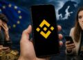 Mano sosteniendo un teléfono con el logo de Binance frente a la bandera de la UE y personas preocupadas.